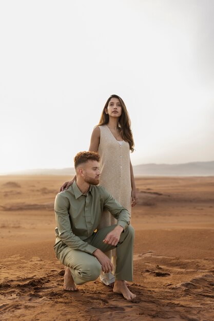 砂漠のフルショットでポーズをとるカップル