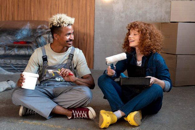 Couple posing together in their new home while holding paintbrush