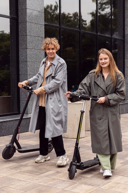 Free photo couple posing with electric scooters outdoors