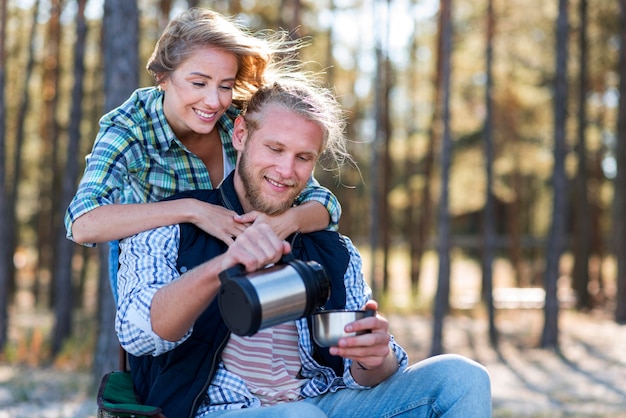 Free photo couple pouring coffee from thermos