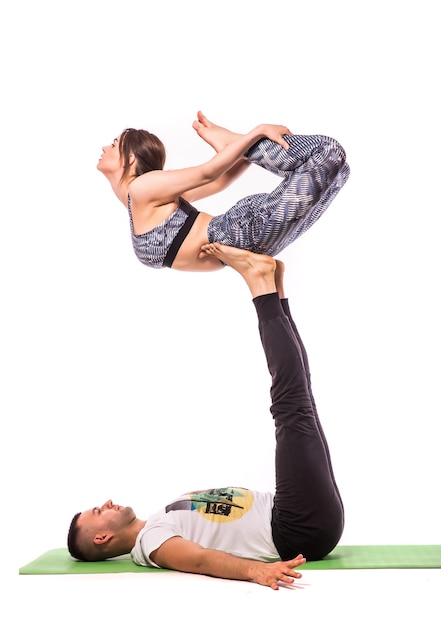 Couple practicing acro yoga in white studio. Acro yoga concept. Pair yoga. Yoga flexibility class workout