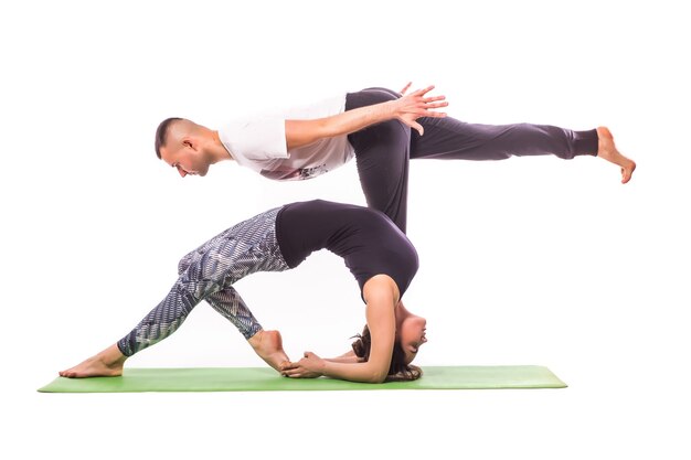 Пара, практикующая акро-йогу в белой студии. Концепция акро-йоги. Парная йога. Тренировка класса гибкости йоги