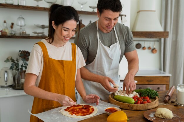 Пара вместе готовит и готовит вегетарианскую пиццу на кухне