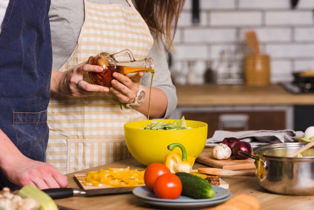 Couple preparing vegetable salad in kitchen