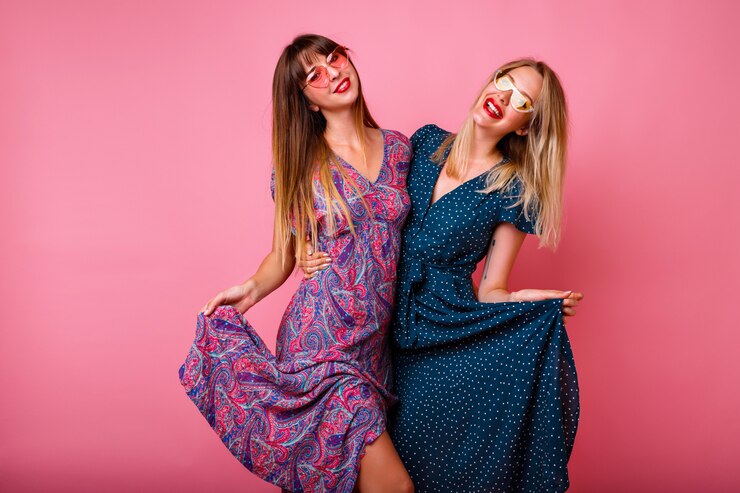 Free Photo couple of pretty best friends sister girls having fun together, wearing elegant summer pretty trendy dresses and sunglasses, posing at pink wall, hugs and smiling, party atmosphere.