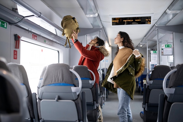 Couple putting their backpacks away and taking their jackets off while traveling by train