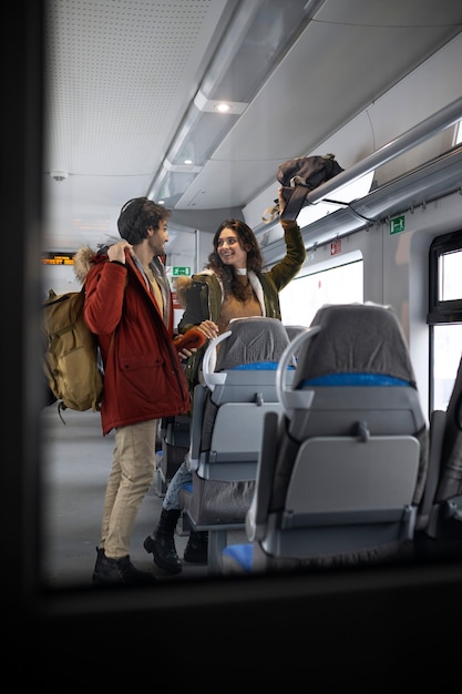 電車で旅行中にバックパックを片付けているカップル