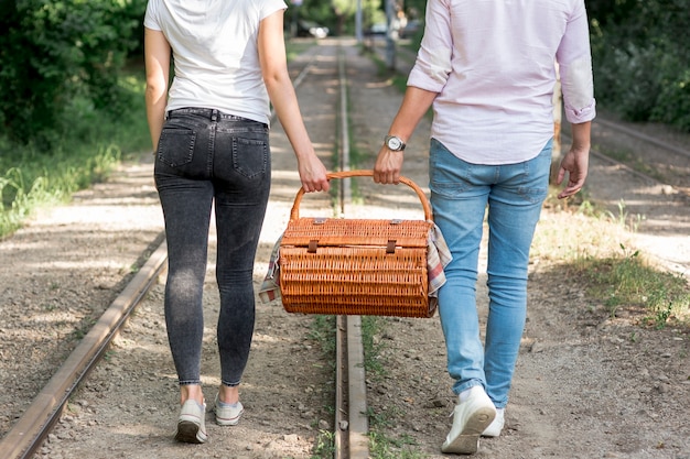 Couple on a railroad carrying a picnic basket