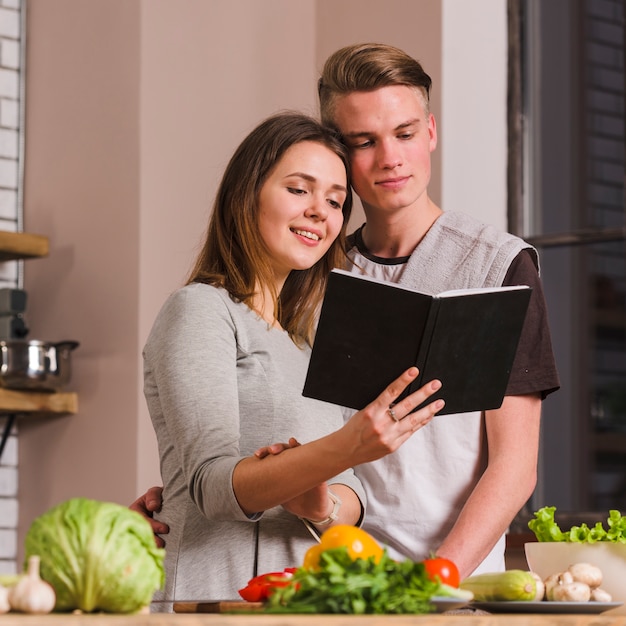 Couple reading book while cooking together 