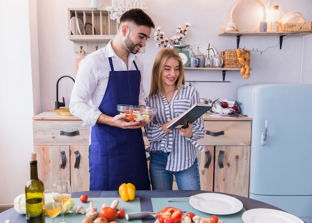 Couple reading recipe book in kitchen 