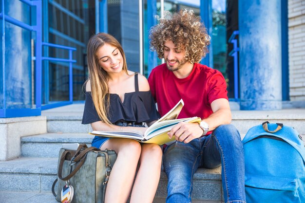 Couple reading textbook near university