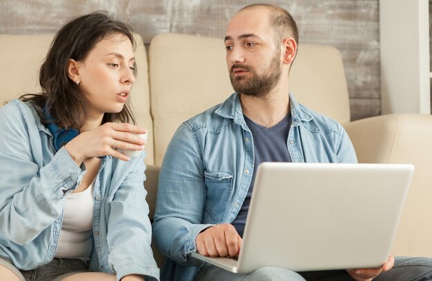 Couple relaxing in living room drinking coffee and browsing on internet