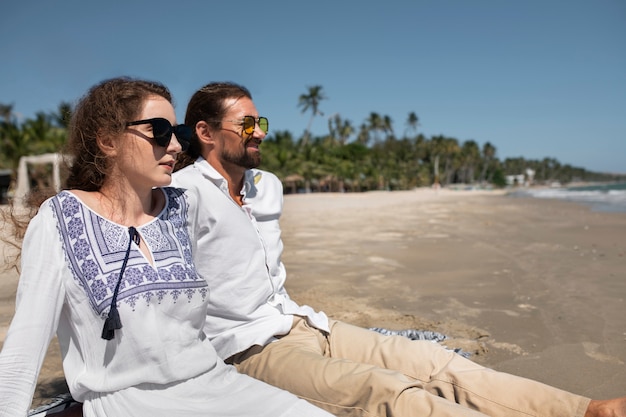 무료 사진 휴가 기간 동안 해변에서 휴식을 취하는 커플