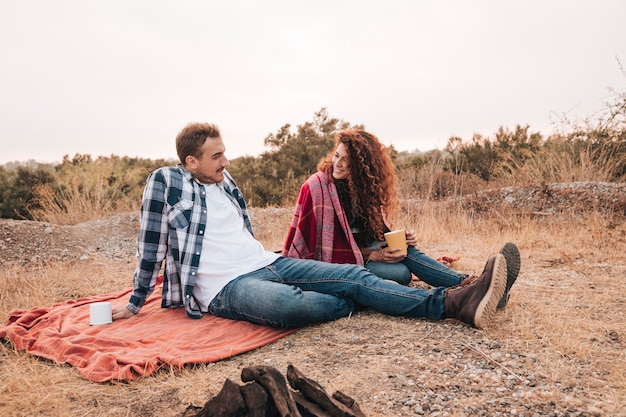 Couple relaxing outdoors next to a camp fire