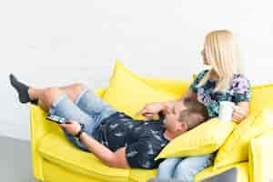 Free photo couple relaxing on sofa and watching television at home