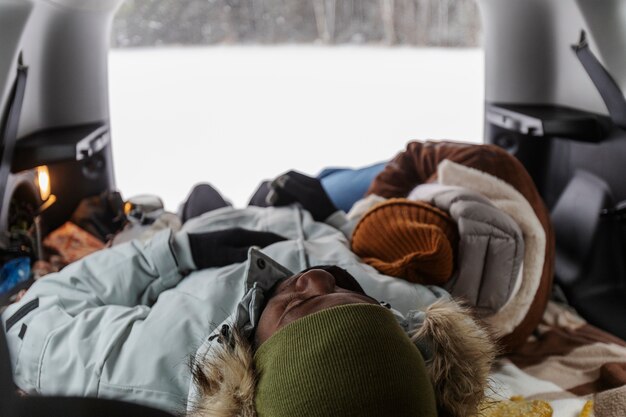 Couple resting inside car's trunk while on a winter road trip together