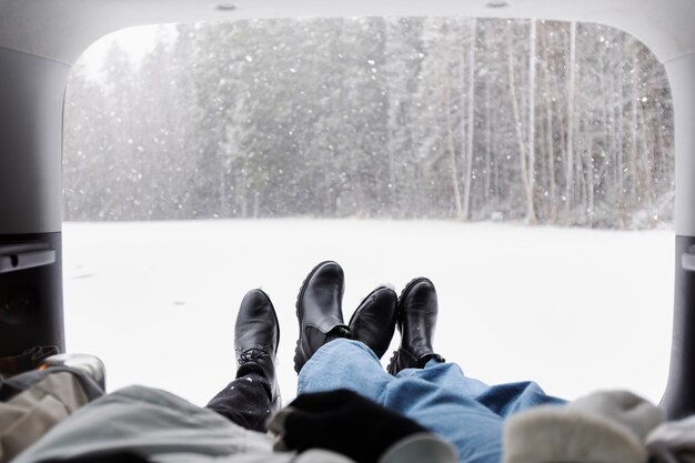 겨울 도로 여행을 함께 하는 동안 자동차 트렁크 안에서 쉬고 있는 커플