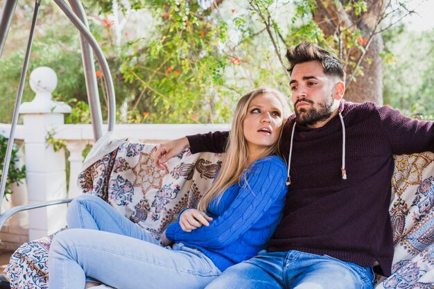 Couple resting on swing sofa outside