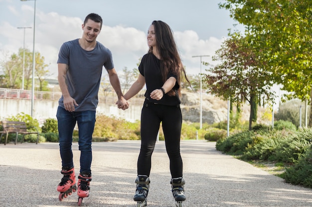 Couple riding roller skates and holding hands