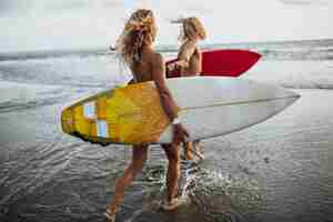 Free photo couple runs along coast to sea. man and woman are going to surf