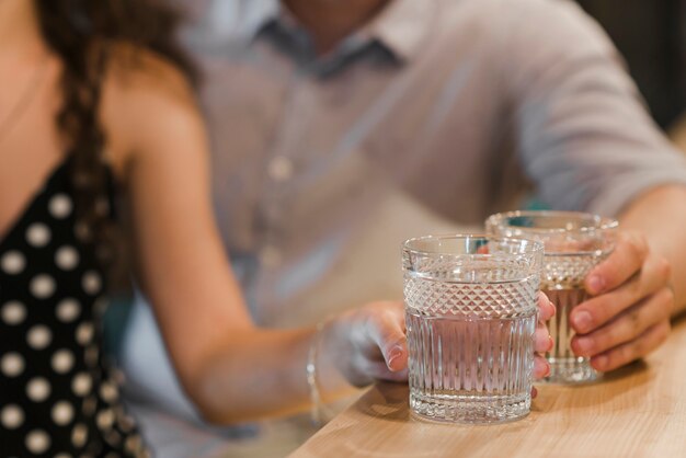 Couple's hand holding glass of drinks at bar counter