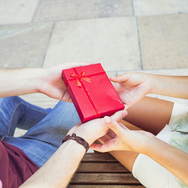 Couple's hand holding red gift box