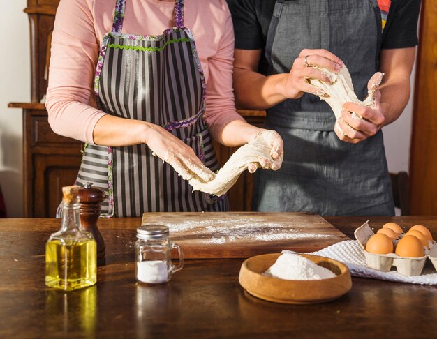 Пара готовит тесто с ингредиентами на деревянной поверхности
