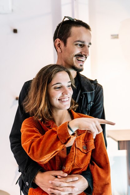 couple scratched from the back, pointing at something and laughing