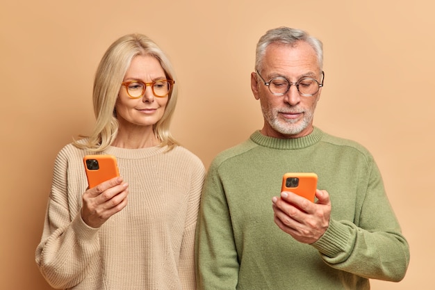 年配の女性と男性のカップルは、ディスプレイに焦点を当てた最新のスマートフォンを使用しています