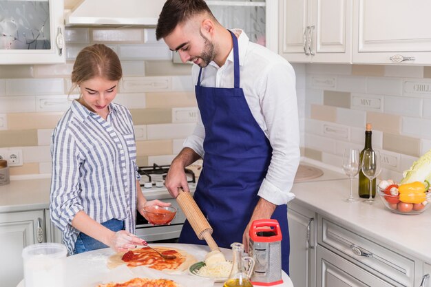 Couple in shirts cooking pizza in kitchen