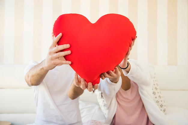 Free photo couple showing heart cushion to camera