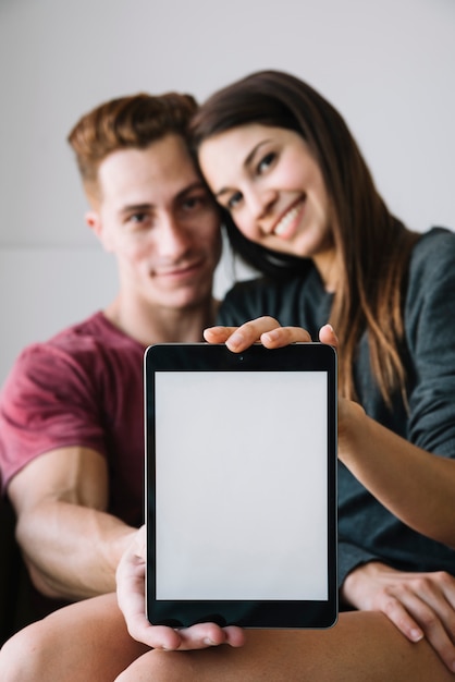 Couple showing tablet with blank screen in hands 