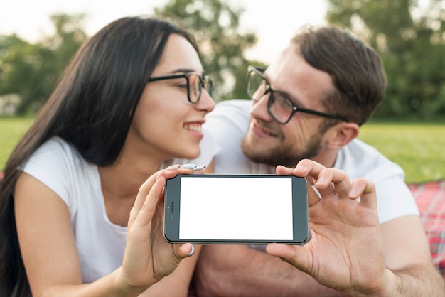 Free photo couple showing technological device in the park