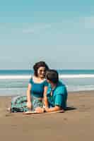 Free photo couple sitting on beach and looking at each other