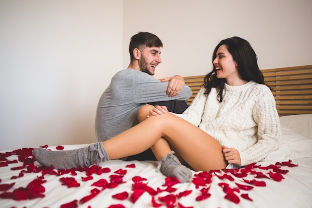 Couple sitting on a bed full of rose petals