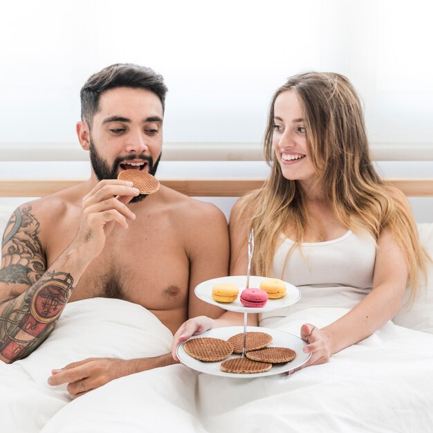 朝の朝食を取るベッドに座っているカップル