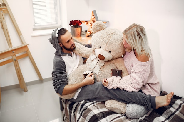 Free photo couple sitting on a bed in a room and drinking coffee