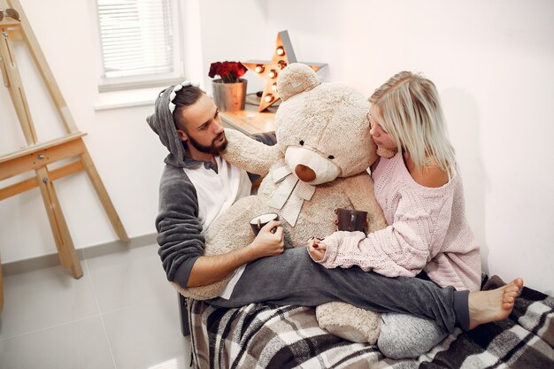 Couple sitting on a bed in a room and drinking coffee