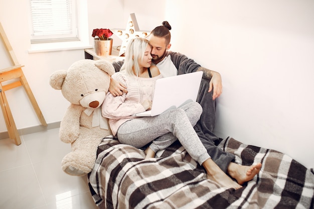 Couple sitting on a bed in a room and use a laptop