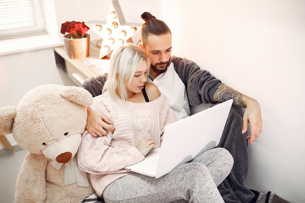 Couple sitting on a bed in a room and use a laptop
