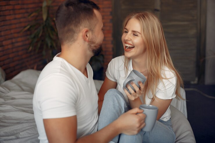 Free Photo couple sitting on a bed in a room