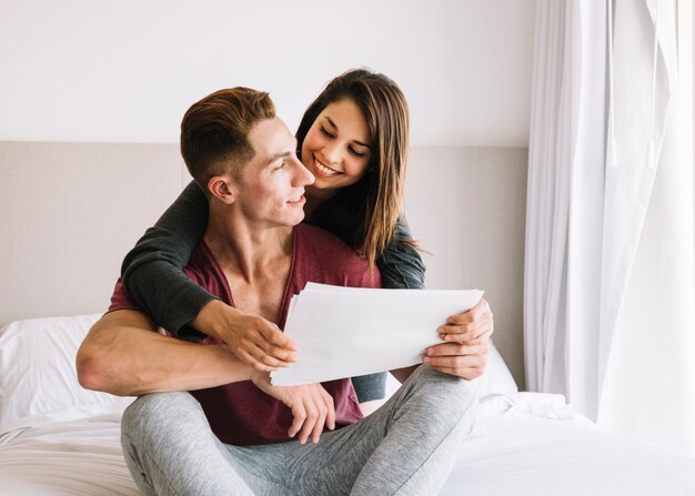 Couple sitting on bed with papers 