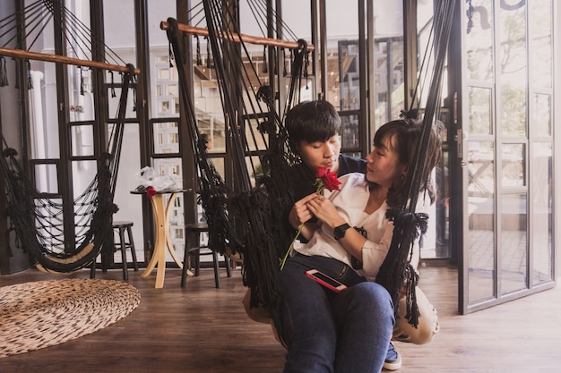 Free photo couple sitting in a black cloth hammock