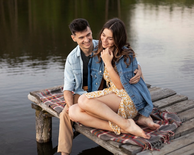 Couple sitting by the lake full shot