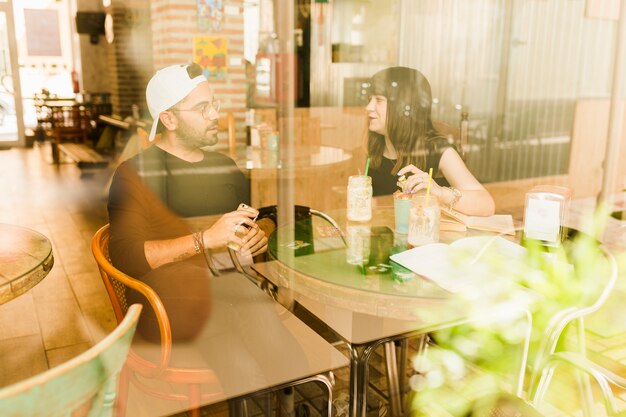 Couple sitting in cafe seen from glass window