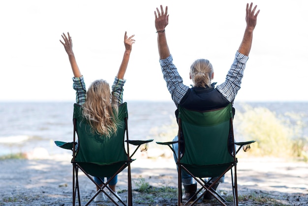 Free photo couple sitting on chairs with hands in the air
