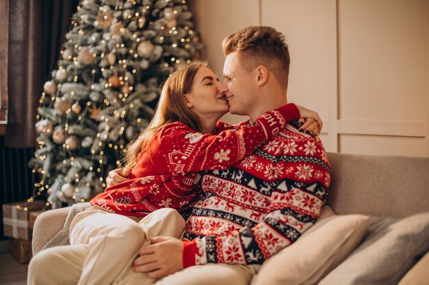 Couple sitting on coach together by the Christmas tree