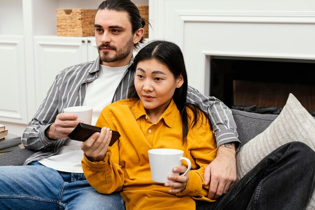 テレビを見ながらソファに座っているカップル