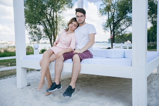 Couple sitting on a double bed at the beach