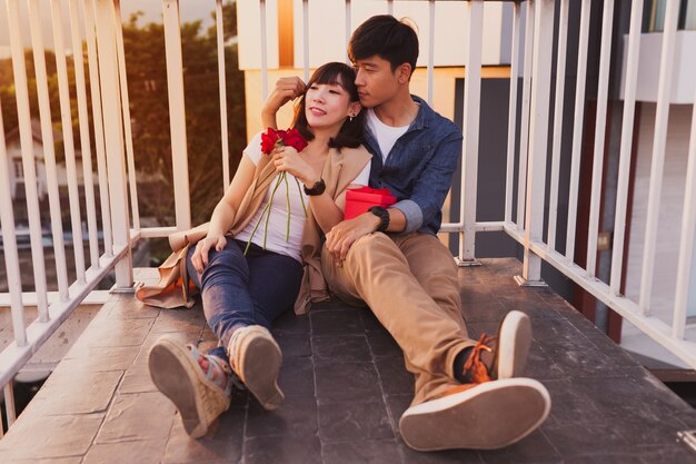 Couple sitting on the floor leaning on a fence